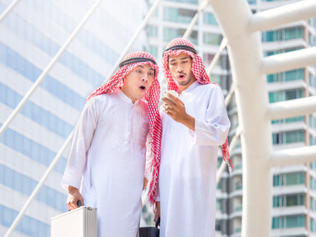 Greeting of arab businessman in the modern city, successful, happy, good feeling, winner, looking at smart phone with smilingの写真素材