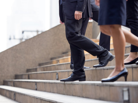 Close up legs of businessman and businesswoman in suit, walking down from stairs, go on business, go down, loss, retired, unemployment and quit from job conceptの写真素材