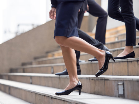 Close up legs of businessman and businesswoman in suit, walking down from stairs, go on business, go down, loss, retired, unemployment and quit from job conceptの写真素材
