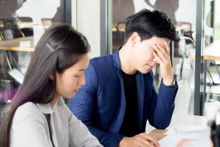 Stressed angry crazy asian business man and woman feeling upset, disappointed during meeting, knowing bad news at cafe officeの写真素材