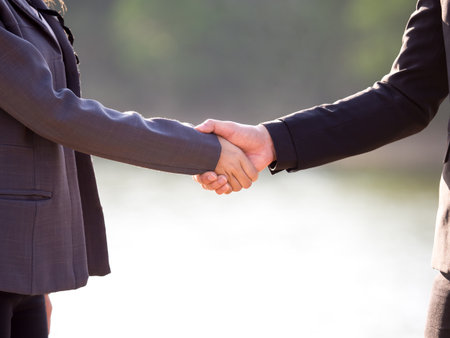 Shaking hands of business man and business woman over the nature blurred backgroundの写真素材
