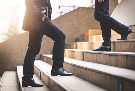 Close up legs of businessman walking stepping up stair in modern city, business growth, go up, success, grow up business conceptの写真素材