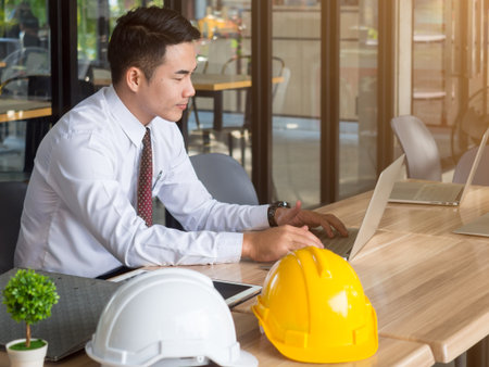 Asian engineer sitting in cafe working for construction plan on labtop in the morning with sunlightの写真素材
