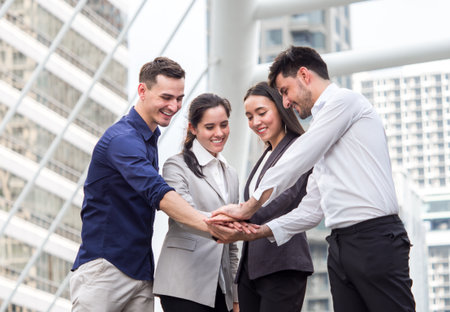 young businessman and businesswoman express teamwork, stacking hands at outdoor officeの写真素材