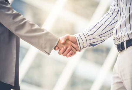 Businessman and businesswoman shaking hands for greeting and meeting at outdoor, teamwork and cooperation concept, vintage toneの写真素材