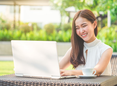 Young beautiful Asian woman working with laptop/internet/online shopping at outdoor park, smile/fresh and happy relaxing feeling in the morning, freelancer working businesswoman lifestyle conceptの写真素材