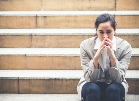 Upset young caucasian beautiful businesswoman tired from work sitting at stairs, unemployment, fired from job, disappointed, loss and feeling down conceptの写真素材