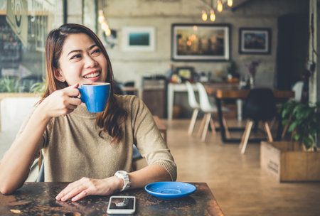 Young beautiful asian woman drinking coffee in coffee shop cafe, vintage tone colorの写真素材