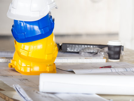 safety helmet for engineer and architect on working desk/table with drawing/blueprint and tools at job site, engineer/architect for construction work conceptの写真素材