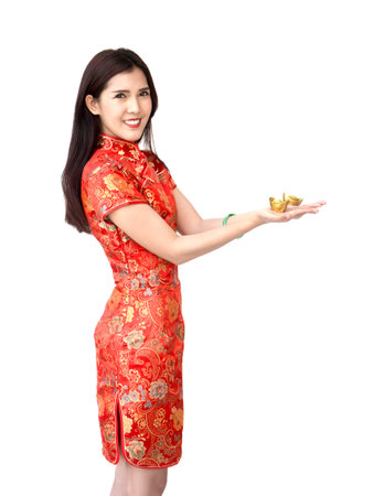 Chinese new year woman concept, isolated asian woman wearing red dress holding gold on handの写真素材