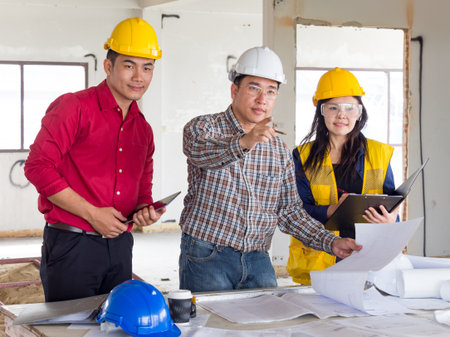 group of engineer/architect/worker man and woman discussing about building plan for construction at job site, working on desk/table with drawing/blueprint/business planの写真素材