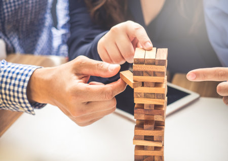 Group of business people building tower by wooden blocks, doing a plan for business strategy, risk,...