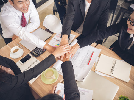 stacking hands of businessman and businesswoman while meeting at office over the meeting desk/table,...