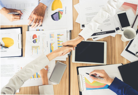 Businesswoman shaking hands during meeting on meeting table/desk with many financial documents, teamwork and cooperation conceptの写真素材