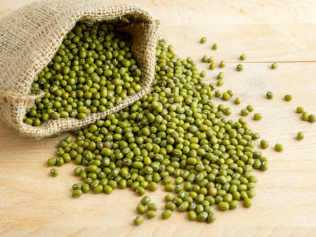 Mung beans(green beans) in a sack, on wood backgroundの写真素材