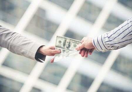close up hand of businessman giving/sending/transfer cash money dollars to businesswoman in the city, banking and financial conceptの写真素材