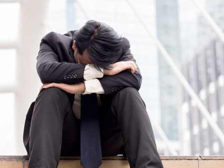 Upset asian businessman 40s tired from work sitting at stairs, unemployment, fired from job, disappointed, loss and feeling down conceptの写真素材