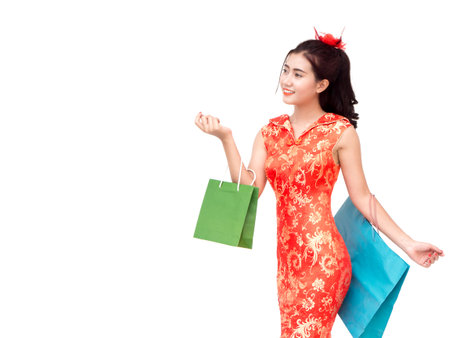Chinese new year woman concept, isolated asian woman wearing red dress holding shoping bagの写真素材