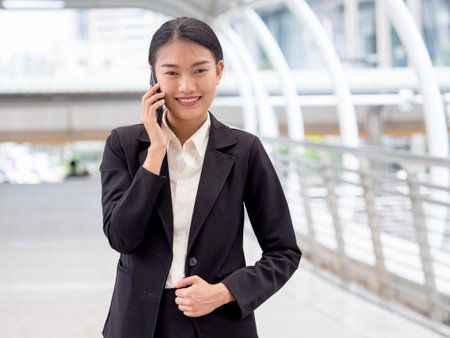 Portrait young Asian businesswoman 20-30s holding smart phone in formal suit at the modern cityの写真素材