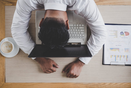 Middle age Asian businessman feeling sleepy during working on laptop and meeting at cafÃ© officeの写真素材
