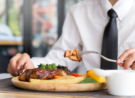 Young businesswoman eating steak, lunch meal at restaurant cafeの写真素材