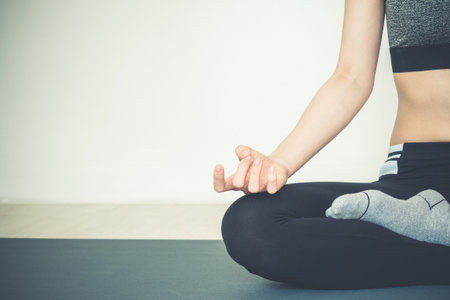 Young beautiful asian woman do yoga pose sitting on yoga mat in fitness classの写真素材