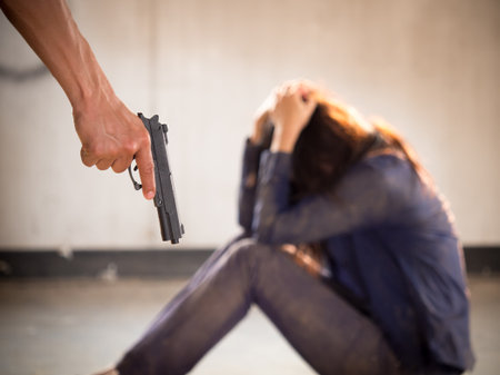 A murderer/terrorist/prisoner man holding gun kidnapping young woman for a hostage/rape/intimidate, violence/robbery/killer concept.の写真素材