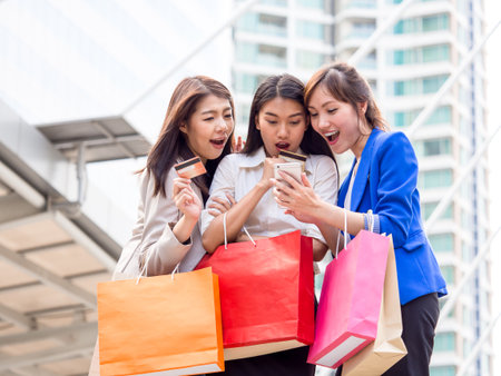 Woman shopping concept, asian woman holding colorful shopping bags and credit cards in shopping mall/city with happy, funny feelingの写真素材