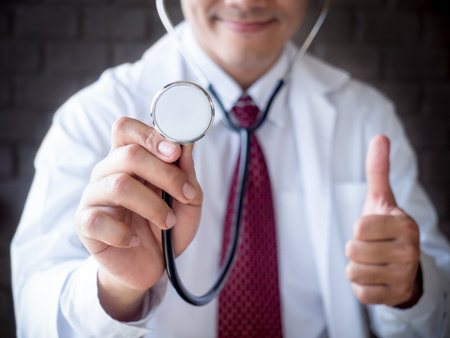 Smiling Asian doctor in uniform holding stethoscope(close up) for medical conceptの写真素材