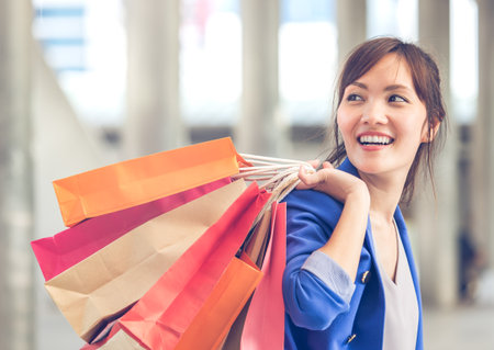 Woman shopping concept, asian woman holding colorful shopping bags in the city/shopping mall, smiling happy funny feelingの写真素材