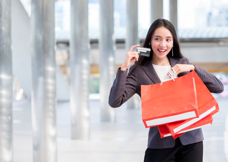 Close up woman holding shopping bag and credit card walking in the city with copy spaceの写真素材
