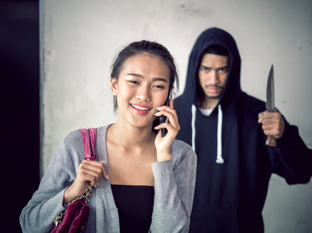 Culprit on hood holding knife is stalking asian woman while walking alone and talking on the phone...