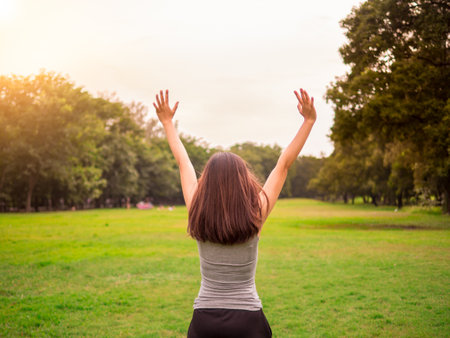 A women raises her hands on the green field, freedom feeling, fresh, morning, good feelingの写真素材