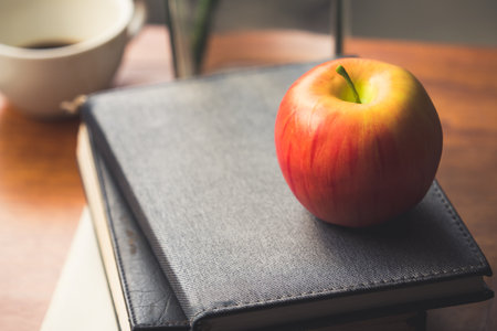 Red apple, book and coffee on table, vintage toneの写真素材