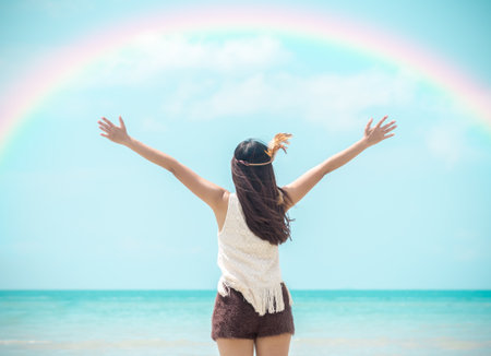 Happy young woman rising hands to sky at sea/beautiful beach, freedom, relaxing on vacation/holiday.の写真素材