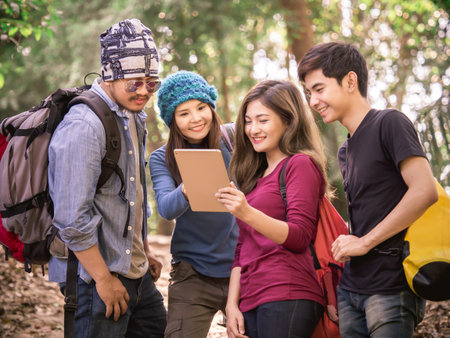 Group of young menwomen using tablet for GPS mapplanning trekkingtraveling in nature forest, backpack traveling for freedom lifestyle with relaxation life outdoor vacationholiday conceptの写真素材