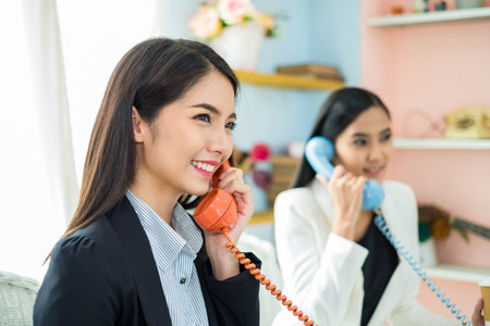 Two young asian business woman working as call center with happy and smile in officeの写真素材