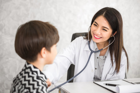 Asian woman doctor, check up heartbeat of kid, healthcare and medical for kid conceptの写真素材