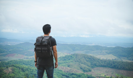 Asian man backpacker/traveler over high view of top mountain landscape in natureの写真素材