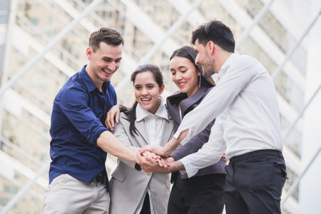 young businessman and businesswoman express teamwork, stacking hands at outdoor officeの写真素材