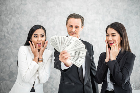 Business man and woman holding money banknotes dollars in formal suit for financial conceptの写真素材