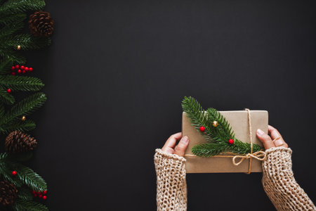 Christmas background with hand holding gift present for christmas and happy new year concept over black background. flatlay topviewの写真素材