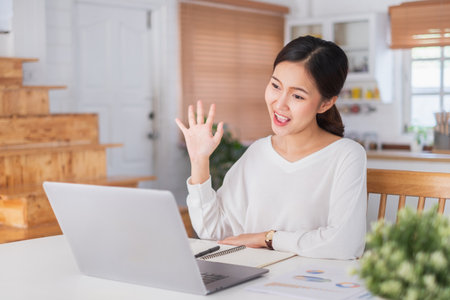Young Asian businesswoman work at home and virtual video conference meeting with colleagues business people, online working, video call due to social distancingの写真素材