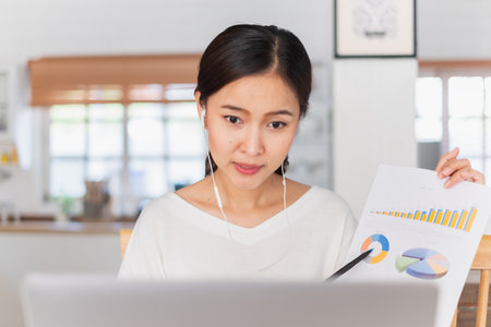 Young Asian businesswoman work at home and virtual video conference meeting with colleagues business people, online working, video call due to social distancingの写真素材