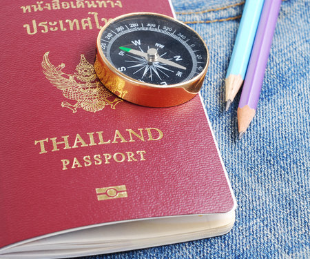 Thailand passport with compass and pencils on jeans jacketの写真素材