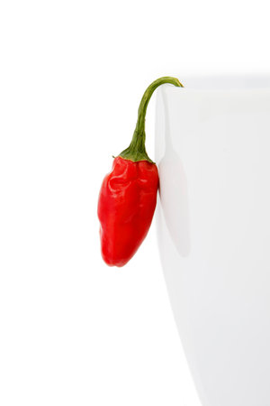 Red Chili Hanging from the Side of a White Bowl, Isolated on White Backgroundの写真素材