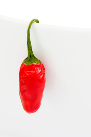 Red Chili Hanging on Side of White Bowl, Isolated on White Backgroundの写真素材