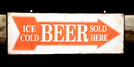 Closeup of an Orange and White Sign indicating the Direction to the Bar - Ice Cold Beer Sold Hereの写真素材