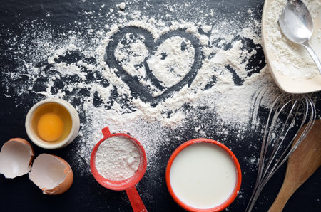 Baking ingredients on a dark, stone table: eggs, flour and milk.の写真素材