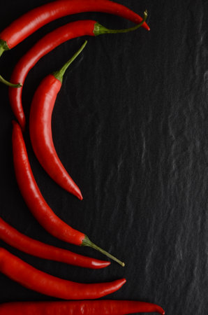Red hot chili peppers on a dark, stone backgroundの写真素材